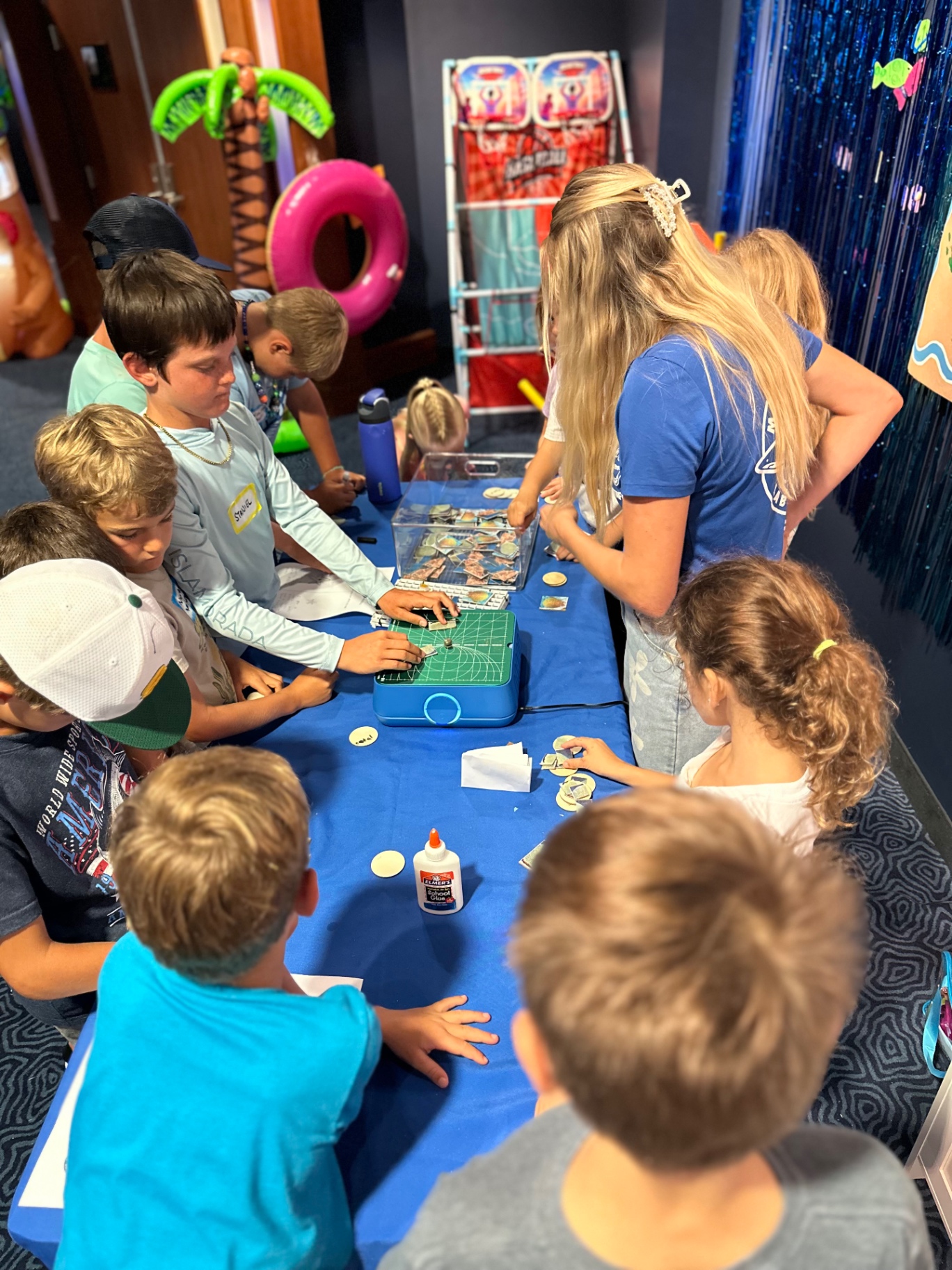 Campers gathered around a craft table with a camp leader