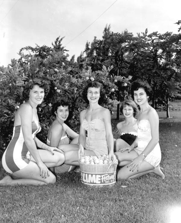 Five women in mid-century swimsuits posed around a large bushel basket piled with limes in front of a banner reading LIME Festival