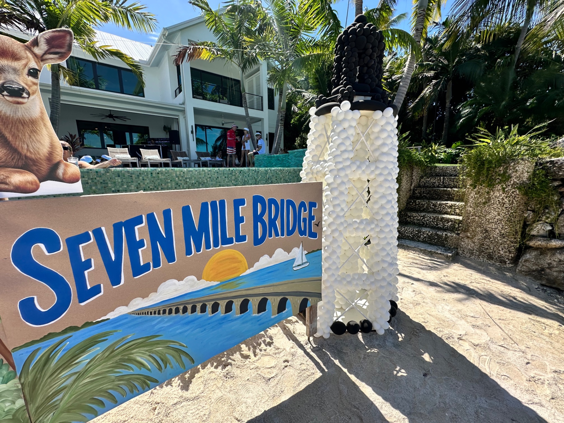 A painted Seven Mile Bridge sign beside a balloon sculpture of a lighthouse
