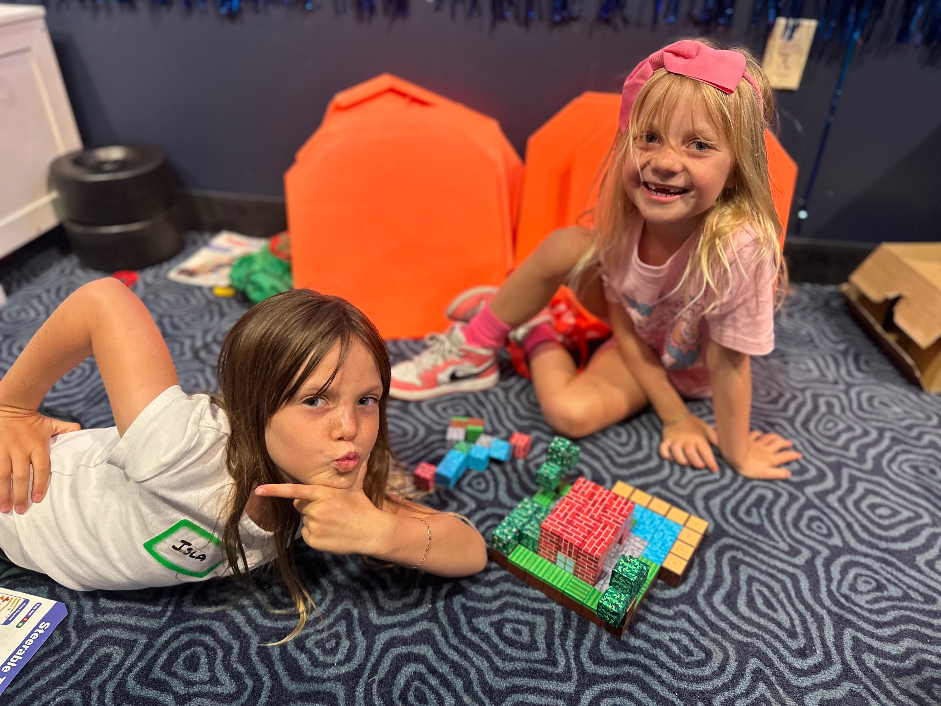 Two campers play with a wooden block building set on the floor