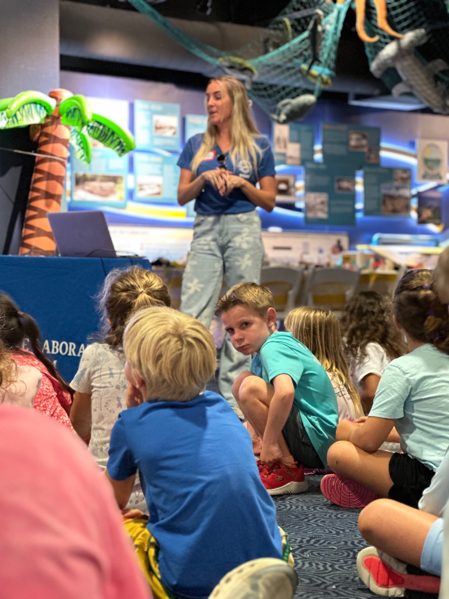 A camp leader speaks to seated campers in the exhibit hall