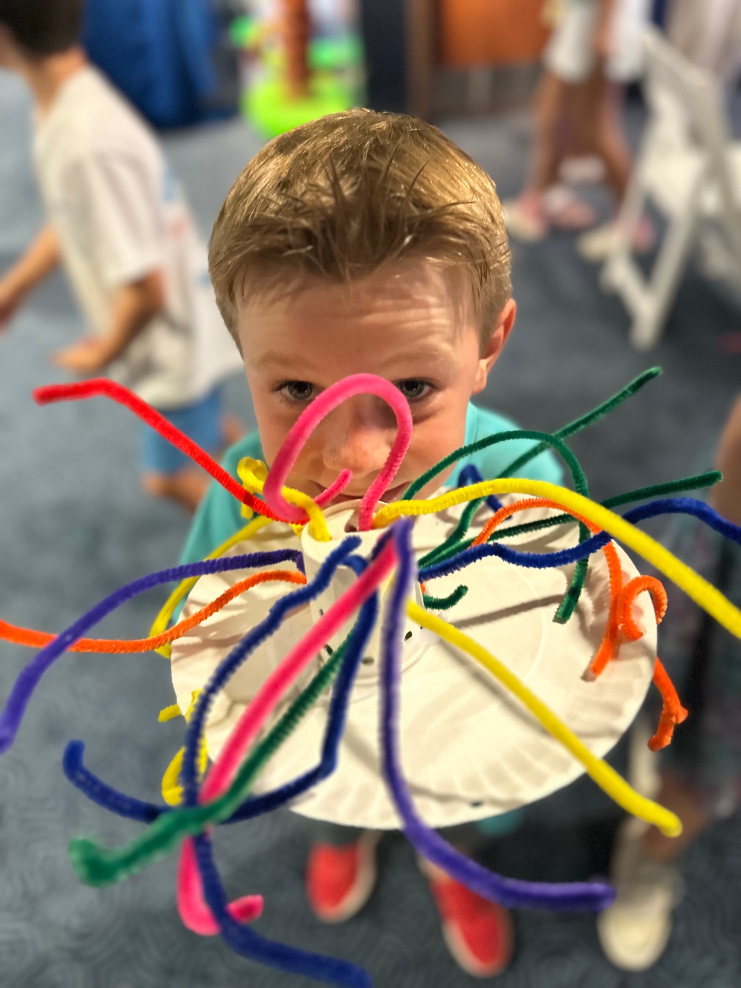 A camper shows off a colorful pipe-cleaner jellyfish craft